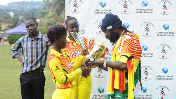 Jamaican Reggae star Riley (R) admires trophies presented to her by the Lady Cricket Cranes skipper Kevin Awino (L) and Janet Mbabazi (C) at the end of the Tarrus Riley Cricket Carnival in Lugogo yesterday